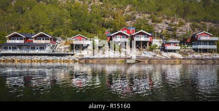 rorbuer - traditional norwegian red wooden house to stand at the lakeside and mountains in the distance, norway Stock Photo