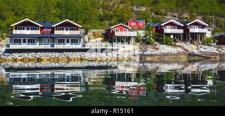 rorbuer - traditional norwegian red wooden house to stand at the lakeside and mountains in the distance, norway Stock Photo