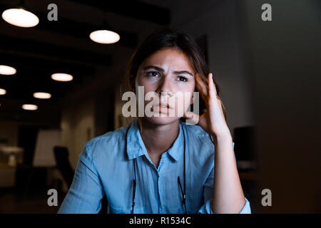 Photo of concentrated young woman graphic designer using pc computer working at night in office. Stock Photo