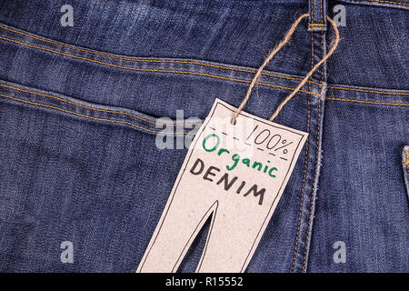 Organic clothes. Close up of blue jeans denim pants with tag. Stock Photo