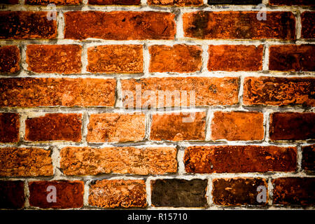 Detail of old and weathered grungy brown and red brick wall marked by the long exposure to the elements as surface texture background with vignetting. Stock Photo