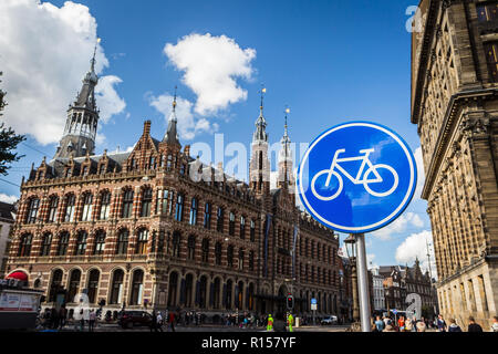 AMSTERDAM, THE NETHERLANDS - September 7, 2018: blue cycle path sign; Magna Plaza shopping mall in the background Stock Photo
