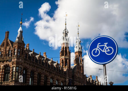 AMSTERDAM, THE NETHERLANDS - September 7, 2018: blue cycle path sign; Magna Plaza shopping mall in the background Stock Photo