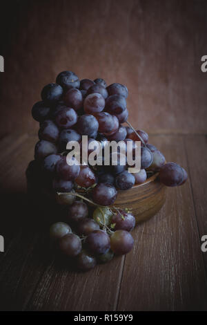 Red grapes lying in a wooden bowl Stock Photo