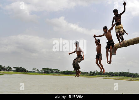 Dhaka, Bangladesh - April 23, 2010: Children jumping and playing at the bank of the Turag River in Dhaka, Bangladesh. Stock Photo