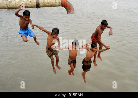 Dhaka, Bangladesh - April 23, 2010: Children jumping and playing at the bank of the Turag River in Dhaka, Bangladesh. Stock Photo