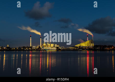 Reflection of the lights of a factory in the water of the river during twilight Stock Photo