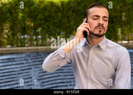 Portrait of young bearded fashionable man talking on phone Stock Photo