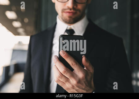 Cropped image of handsome business man near business center using mobile phone. Stock Photo