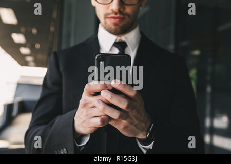Cropped image of handsome business man near business center using mobile phone. Stock Photo