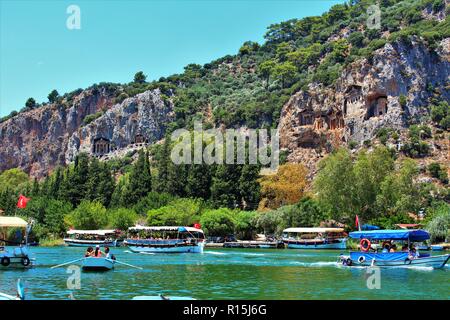 Dalyan, Turkey - July 7th 2018: The Lycian Tombs landmark above the Cayi river, filled with boats and tourists. Stock Photo