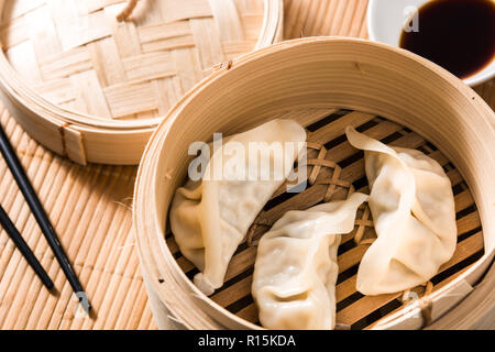 Dumplings or gyoza served in traditional steamer on bamboo mat Stock Photo