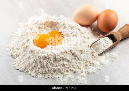 pile of flour with egg yolks for dough on table Stock Photo