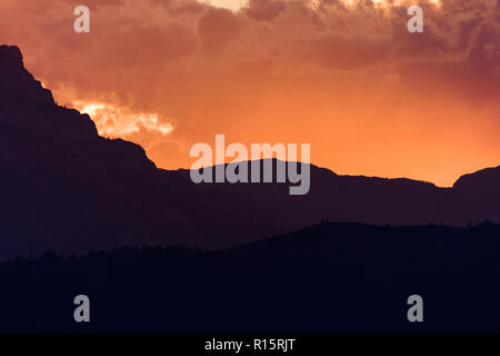 Sun peaks out from behind the clouds over Crowsnest Mountain and Seven Sisters Mountain Stock Photo