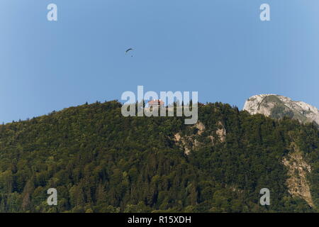 Paraglider flying above a house on the mountain top above Lake Annecy France Stock Photo