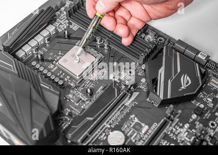 Engineer applying thermal paste on the computer board chip cpu. Stock Photo