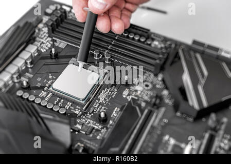 Engineer applying thermal paste on the computer board chip cpu. Stock Photo