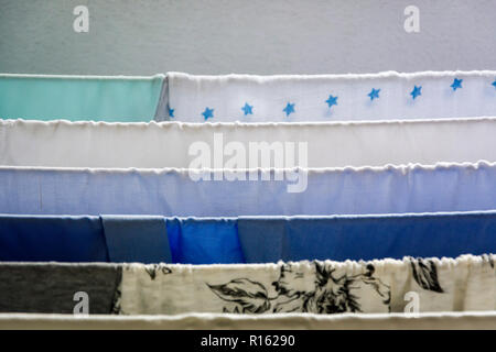 Different types of clothes left hanging to dry on a clotheshorse Stock Photo