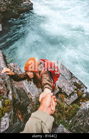 Travel couple helping hand holding together on rocks over river man and woman family adventure lifestyle vacations outdoor exploring wilderness Stock Photo