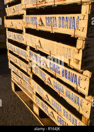 Wooden fish crates stacked labeled with the words Fresh Fish in Catalan, Peix Fresc, and the name of the region Costa Brava. Stock Photo