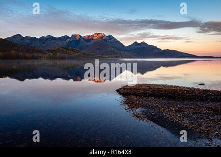Autumn sunrise at Kjerringøy, Norway, with a big lake reflecting the mountains in the background. Stock Photo