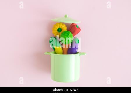 Vegetables falling in kitchen cooking casserole pot abstract isolated on rose. Stock Photo