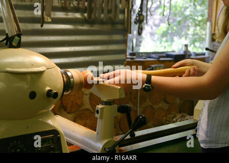 Close up of a young female woodworker turning a wooden bowl on a lathe in a woodworking studio Stock Photo