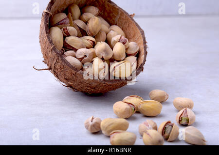 handmade bowl of coconut with pistachios isolated on a white background. Close-up. Stock Photo