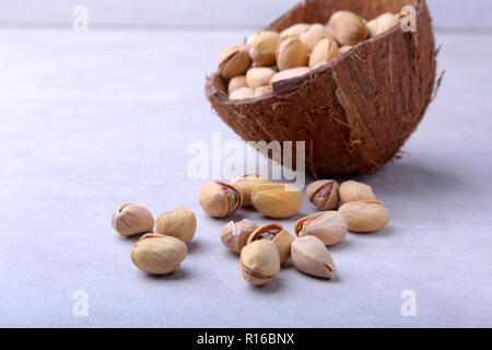 handmade bowl of coconut with pistachios isolated on a white background. Close-up. Stock Photo