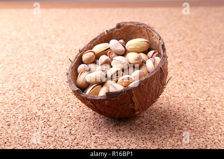 handmade bowl of coconut with pistachios on a wooden table. Close-up. Stock Photo