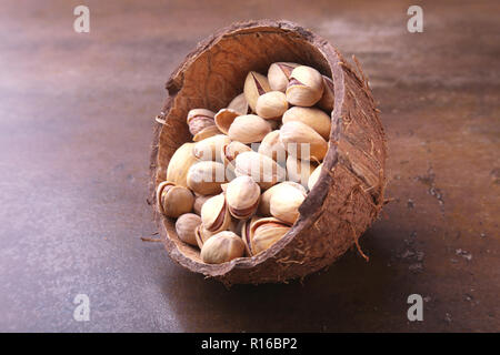 handmade bowl of coconut with pistachios on a stone table. Close-up. Stock Photo