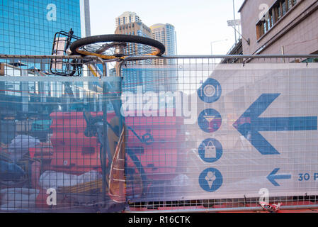 Safety fencing or hording fence around the Light Rail construction site at Circular Quay, Sydney with a hire bike suspended from a fence panel Stock Photo