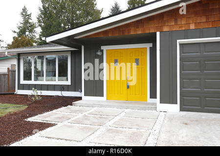 Main entrance of grey single family house accented with yellow double doors. Stock Photo