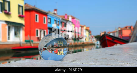 very colorful houses of Burano near Venice in Italy and a large glass sphere with the reflection of the village Stock Photo