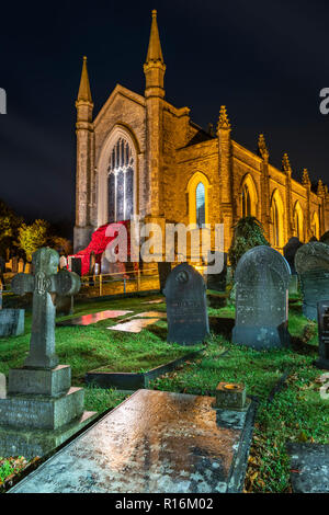 Devon, UK. 9th Nov, 2018. As the rain falls on a wet and windy night, the small North Devon village of Appledore remembers the fallen with a 'Cascading Poppies' window at the local church, made from knitted poppies contributed by the local community. Credit: Terry Mathews/Alamy Live News Stock Photo