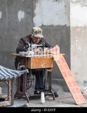 Chinese gentleman earning a living using a sewing machine. China Stock Photo