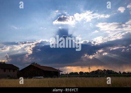 Changing Weather with Sunbeams above Field with Hut, Germany. Stock Photo