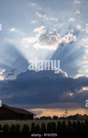 Changing Weather with Sunbeams above Field with Hut, Germany. Stock Photo