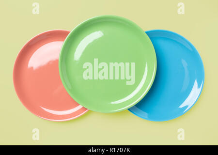 Blue, green and rose pastel colored plates on light yellow background, pop art syle, view directly from above Stock Photo