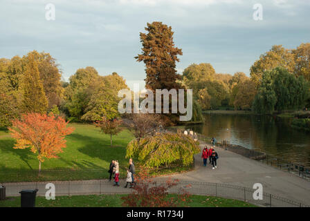 Historic St James's Park in the afternoon sunshine with autumnal colours. People walking in the distance by the lake. Stock Photo