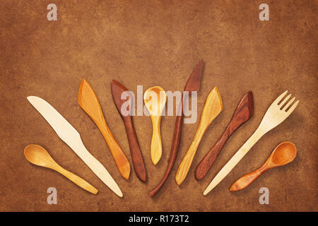 Handcrafted wooden utensils on brown leather background. Fork, spoons and knives. Stock Photo