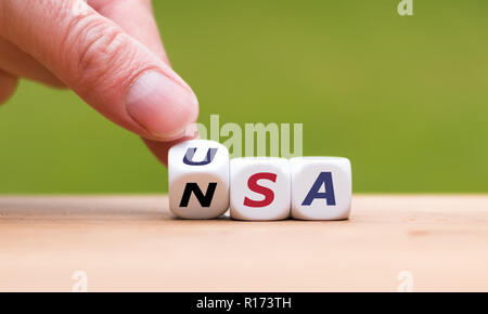 Hand is turning a dice and changes the word "NSA" to "USA" Stock Photo