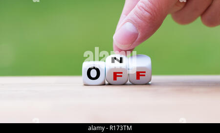 Hand turns a dice and changes the word "off" to "on" Stock Photo