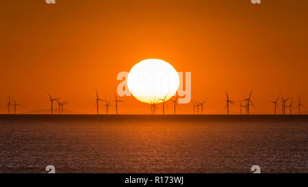Sunset over the Sea with wind turbines on the horizon Stock Photo