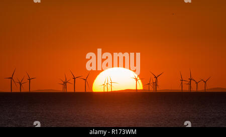 Sunset over the Sea with wind turbines on the horizon Stock Photo