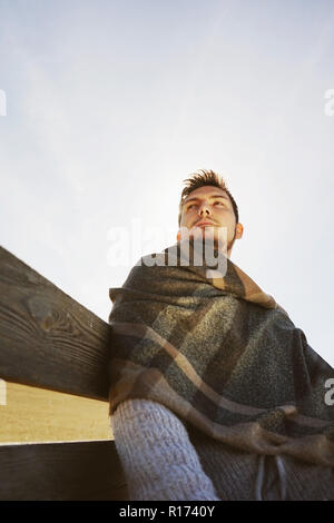 A head-on young man enjoying the calm morning autumn sun with the backlight glow from the blue sky Stock Photo