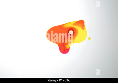 Translucent puddle of orange and yellow paint on white background Stock Photo