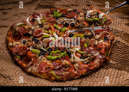 medium pizza with black olives, italian sausage, linguica, mushrooms, onions, peppers, salami, pepperoni Stock Photo