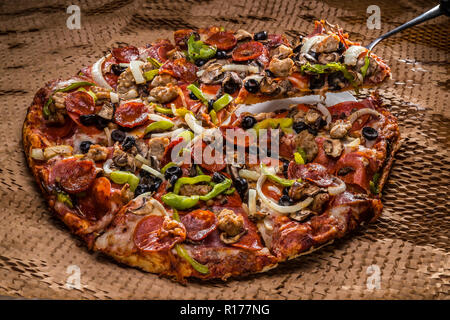 medium pizza with black olives, italian sausage, linguica, mushrooms, onions, peppers, salami, pepperoni Stock Photo