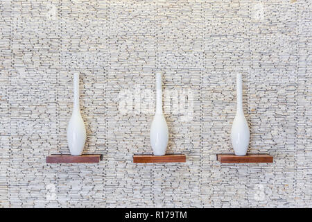 Decorative vases on wooden shelf on white stone texture background Stock Photo